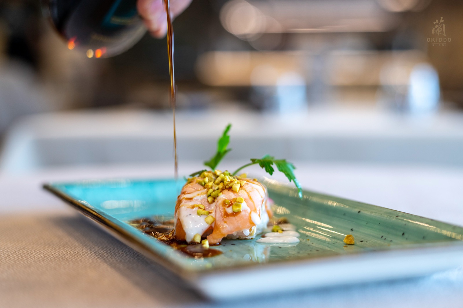 Tartare con salsa versata al tavolo su piatto turchese